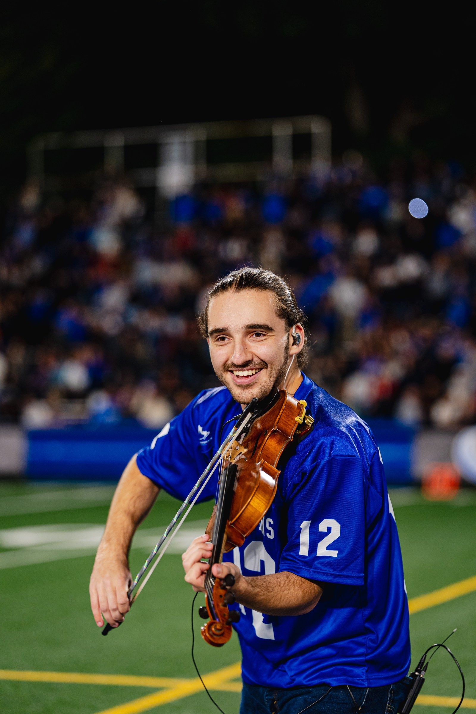 Antoine Fradkin joue du violon devant les gradins d’un stade