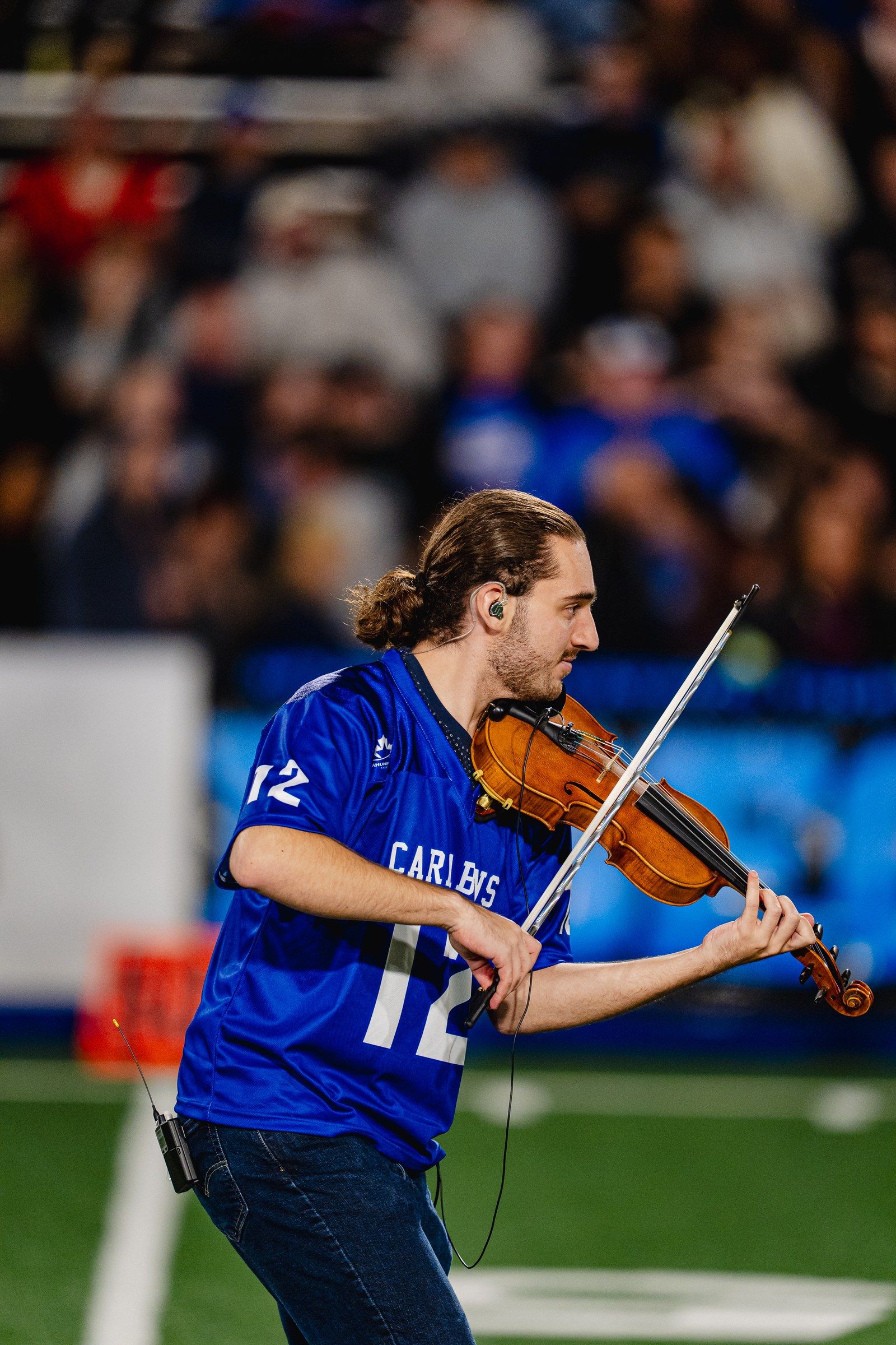 Antoine Fradkin joue du violon sur le terrain lors d’un match de football des Carabins